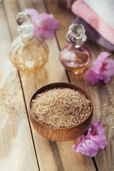 Sea salt, natural handmade soap, natural cosmetic oil and colorful towels with azalea flowers on rustic wooden background