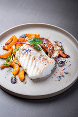 Fried Danish skrei cod fish filet with pumpkin, mushroom and lettuce as closeup on a modern design plate