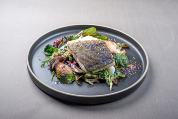 Fried Danish skrei cod fish filet with porcini mushroom and lettuce as closeup on a modern design plate with copy space