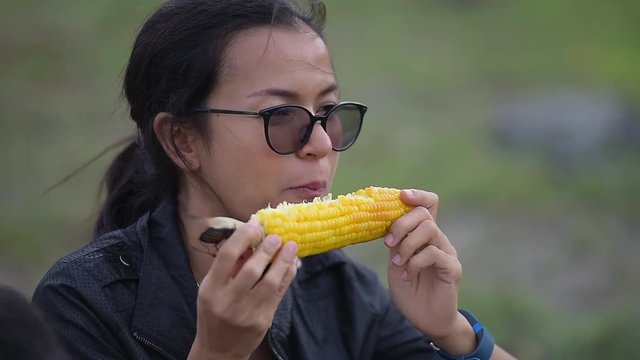 asia woman eating yellow boiled corn