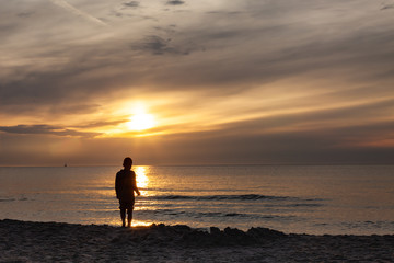 Fototapeta na wymiar Child on the beach, sunset over polish sea baltic