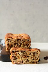 Pancake pie with meat and mushrooms on a gray background. Pancake cake in the form of bread. Slavic cuisine. Pancake pie with meat and mushrooms on a gray background, copy space. Shrovetide Maslenitsa