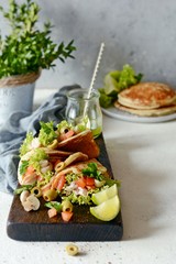 Unsweetened pancakes with turkey, lettuce, tomatoes, pickled mushrooms, olives and greens in the form of tacos on a wooden board. tasty snack of their pancakes and vegetables. Healthy eating concept