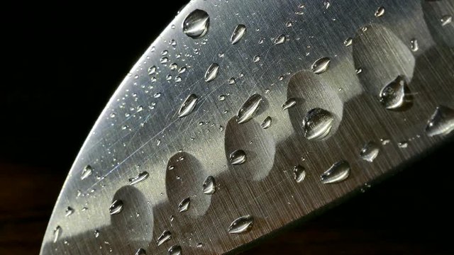 Chef's knife close-up. Knife santoku. blade blade. Drops of water flow down the blade of a knife. Cut vegetables. Cook lunch. Reflection of cold weapons.