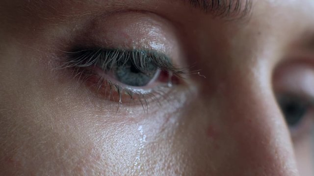The female eye cries and tears are flowing macro video. Close-up woman eye cries and tears flow. 4k. Macro shoot.