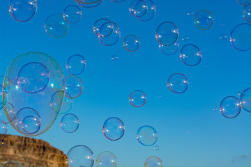 Many soap bubbles in air, blue sky, outdoor fun for everybody