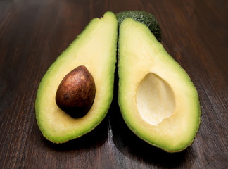 green avocado with a bone cut in half on a wooden table
