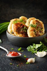 Homemade savory pancakes with minced meat pieces, dill, parsley and green onions, garlic, tomato sauce and chili peppers on a dark background. Snack option pancakes. Fritters with minced meat