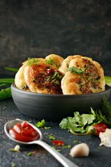 Homemade savory pancakes with minced meat pieces, dill, parsley and green onions, garlic, tomato sauce and chili peppers on a dark background. Snack option pancakes. Fritters with minced meat