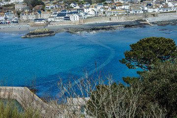 Obraz premium a view from the top above the tree tops to the seafront and land-based seaside village; Under the water there is a path to the island