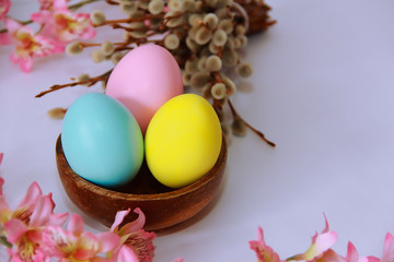 pink yellow blue eggs against a background of willow and flowers for the Easter holiday