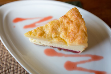 A piece of strawberry cheese cake with strawberry sauce on white plate.