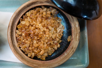 Closed up of rock sugar brown color in round ceramic bowl on green plate.