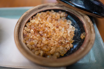 Closed up of rock sugar brown color in round ceramic bowl on green plate.
