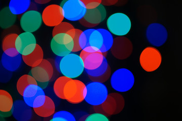 Multi-color blue holiday garland. Garland is blurred. Many big colorful round lights. Fully defocused photo. Blurred background and foreground. Holiday mood. New Year and Christmas is coming.