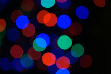 Multi-color blue holiday garland. Garland is blurred. Many big colorful round lights. Fully defocused photo. Blurred background and foreground. Holiday mood. New Year and Christmas is coming.