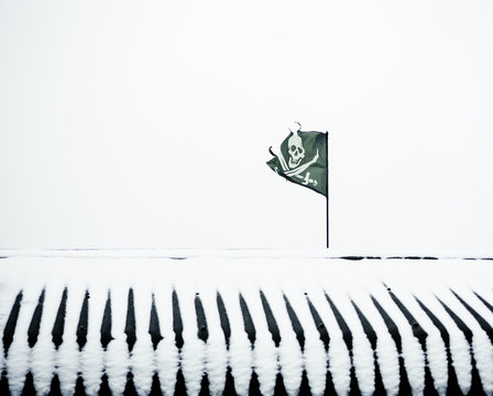 A ragged black pirate flag on a snow-covered roof.