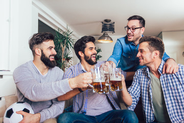 Men watching sport on tv together at home screaming cheerful. Group of friends sitting on the couch and watching a football game.