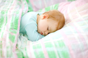 Adorable little baby girl sleeping in bed. Calm peaceful child dreaming during day sleep. Beautiful baby in parents bed. Sleeping together concept.