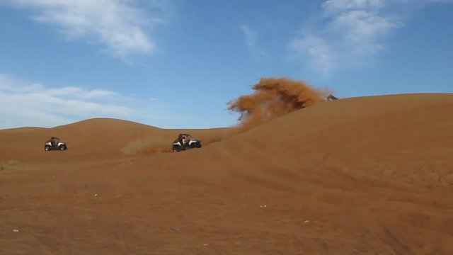people ride sport cars buggies in the sand dunes in the desert