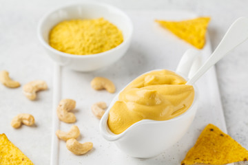 Vegan Cashew Cheese Sauce in white sauceboat, white background.
