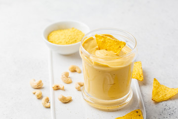 Vegan cashew cheese sauce in a glass, white background.