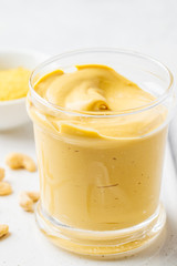 Vegan cashew cheese sauce in a glass, white background.