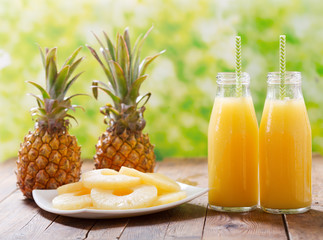 Fototapeta na wymiar bottles of pineapple juice with fresh fruits