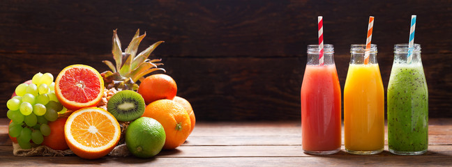 bottles of fruit juice and smoothie with fresh fruits