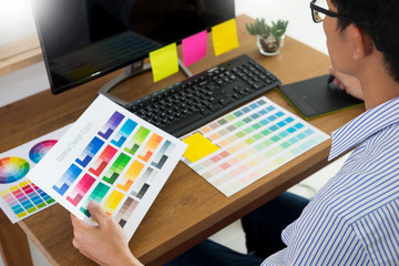 designer Editor at work drawing sketches a new project on graphic tablet and color palette sitting at desk with computer at studio or office