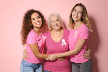 Group of women with silk ribbons on color background. Breast cancer awareness concept