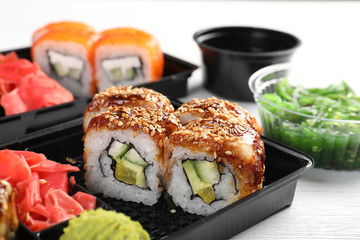 Box with tasty sushi rolls on table. Food delivery