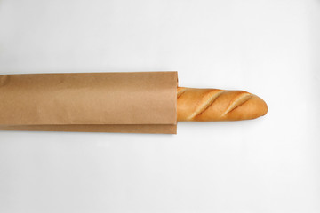 Paper bag with baguette on white background, top view. Space for design