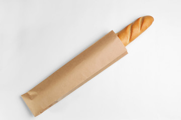 Paper bag with baguette on white background, top view. Space for design