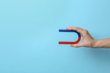 Woman holding magnet on color background, closeup. Space for text