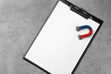 Clipboard and magnet with iron powder on grey background, top view. Space for text