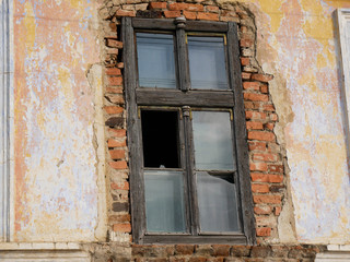 Fototapeta na wymiar Wooden , broken window on abandoned crumbling brick house in Romania.