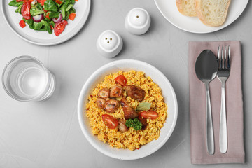 Delicious rice pilaf served on grey table, flat lay