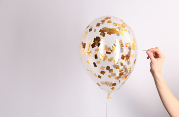 Woman piercing balloon with needle on white background, closeup