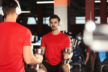 Young man with headphones listening to music and working out at gym