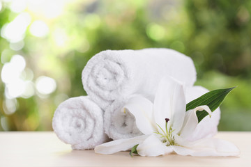 Obraz na płótnie Canvas Soft bath towels and flower on table against blurred background