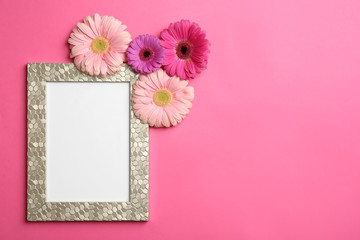 Flat lay composition with stylish photo frame and beautiful flowers on color background, space for text