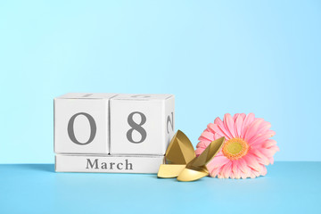 Composition with calendar and flower on table against color background, space for text International Women's Day