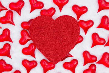 Red glitter heart with red hearts on white fabric background