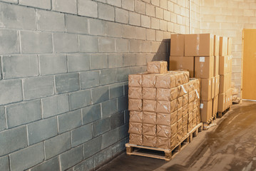 Cardboard boxes on pallets in a warehouse near the concrete wall