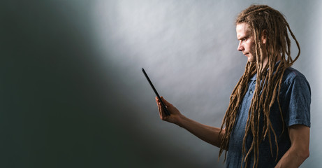 Young man using his tablet on a dark gray background