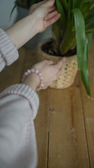 the girl on her arm has a bracelet made of pink stones (quartz), a bracelet made of quartz, hands, indoor flowers (vertically).