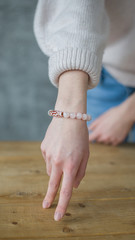 the girl on her arm has a bracelet made of pink stones (quartz), a bracelet made of quartz