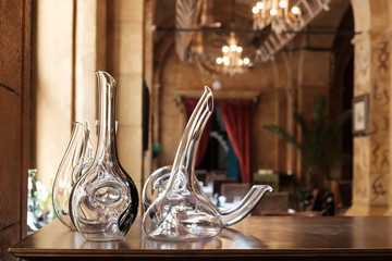Empty elegant glass decanters standing on wooden table in restaurant