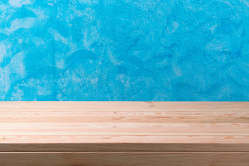 Empty wooden table over blue painted wall background.